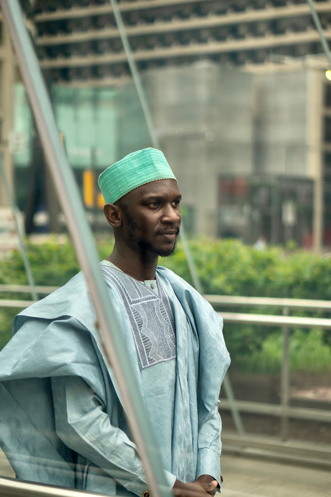 Close portrait, man in agbada with green cap, glass reflection