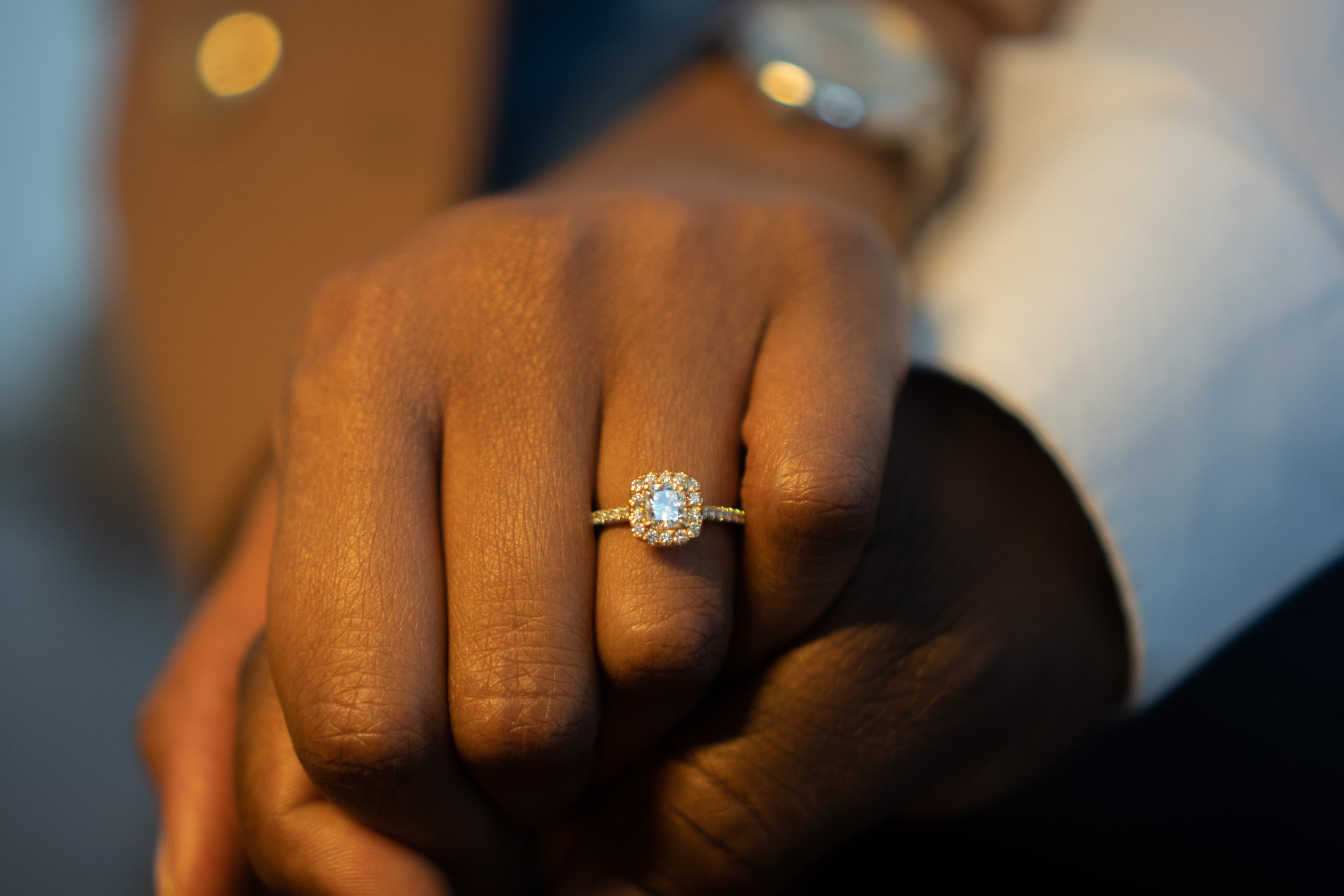 Detail shot, engagement ring on clasped hands