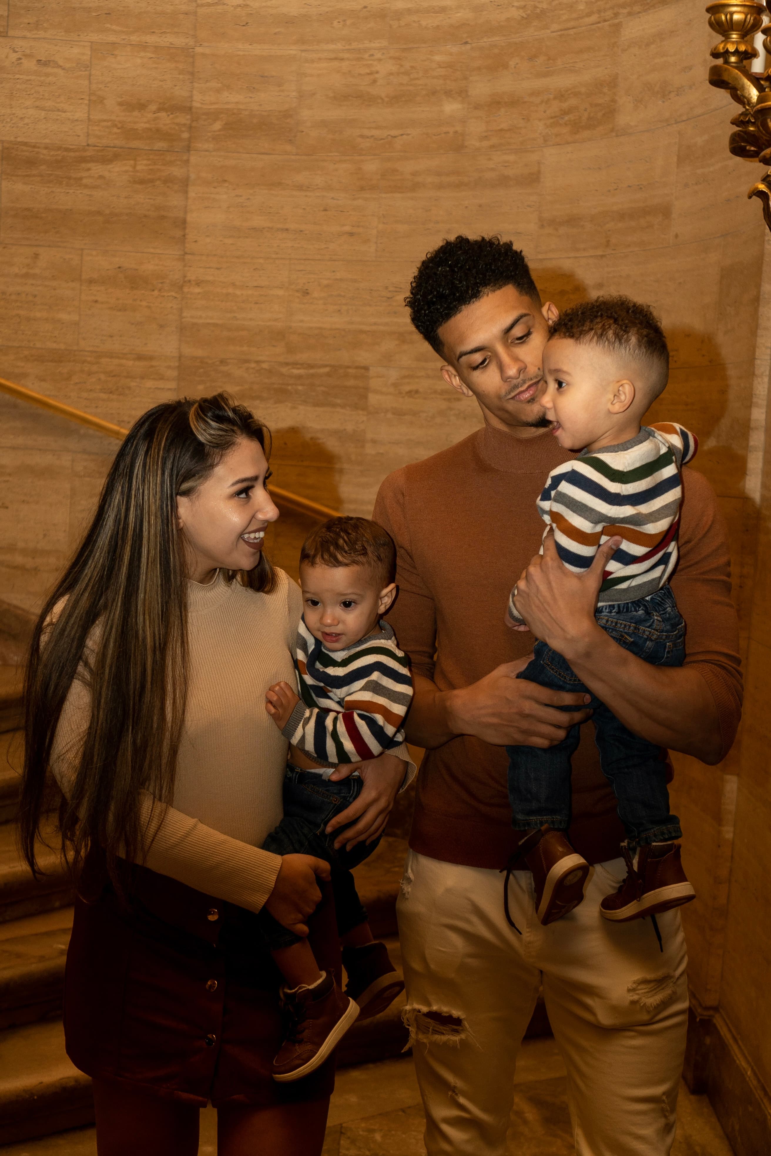 Family portrait, couple with two toddlers on warm marble staircase
