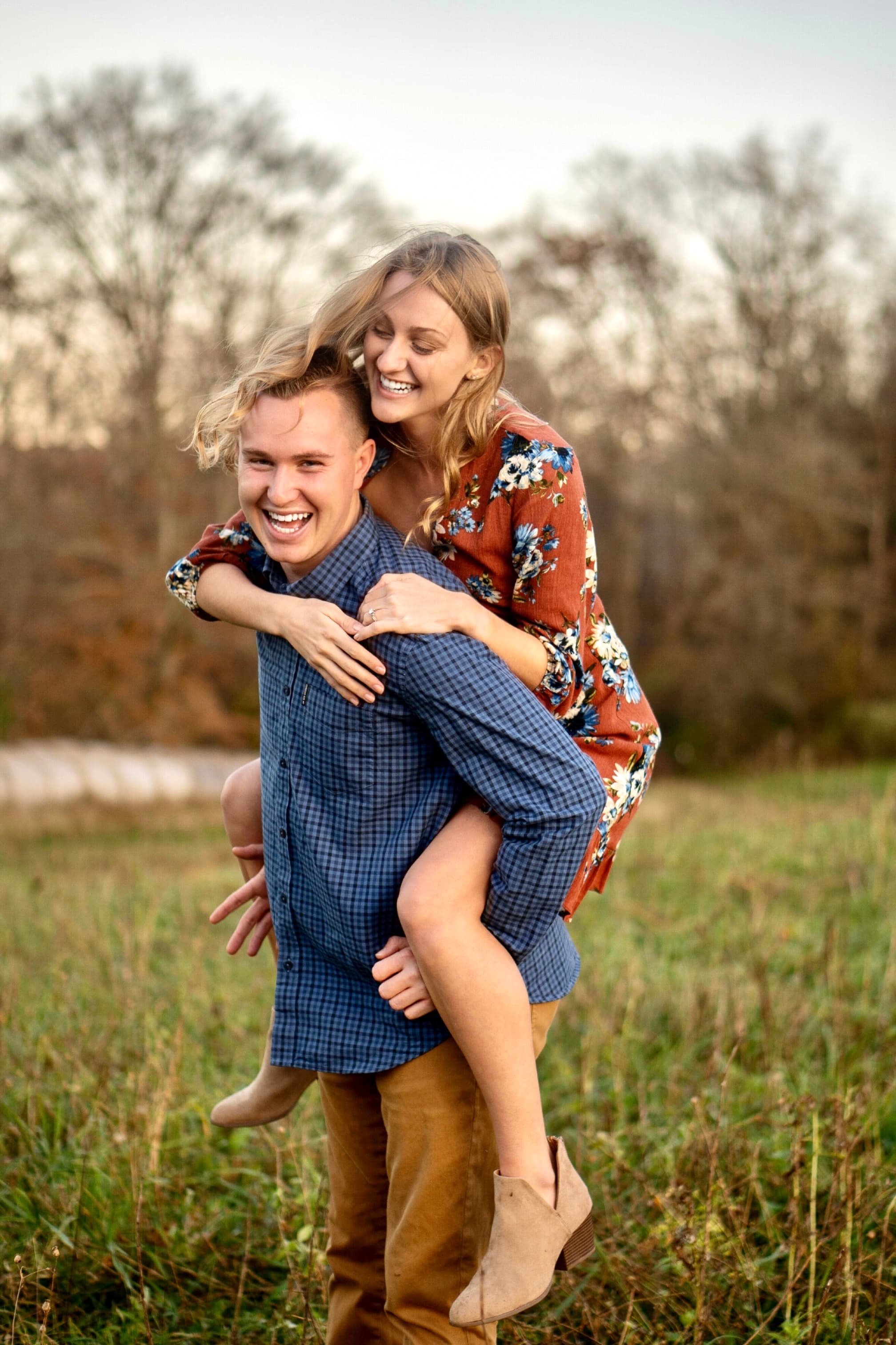 Couple laughing, piggyback in autumn field
